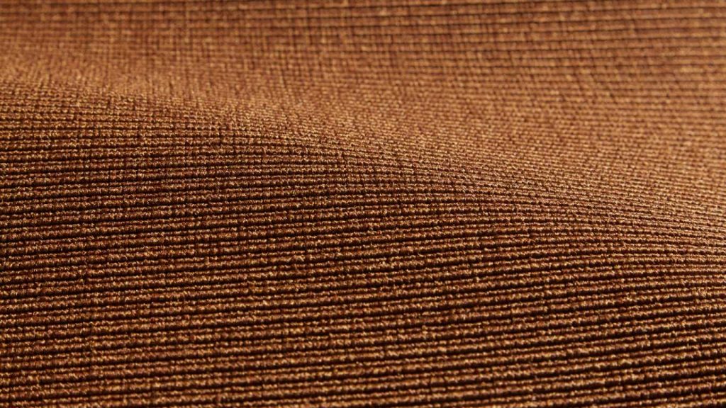 close up pf ribbed texture of orange tone flat weave carpet 
