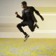 man leaping over yellow patterned carpet tiles